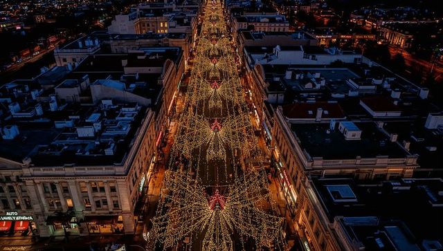 Aerial night boulevard draping golden holiday lights and star ornaments