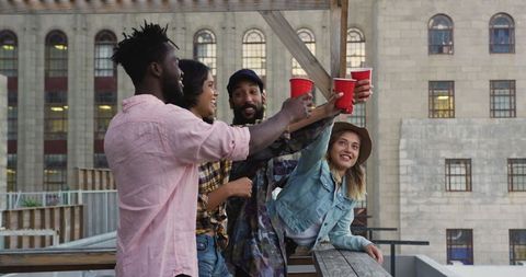 Diverse friends toasting at rooftop party in urban setting