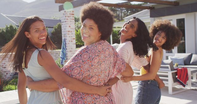 Three women and a girl standing outside with their arms around each other, all smiling and looking back. The scene exudes a sense of joy and camaraderie, perfect for promoting themes of friendship, joy, and outdoor enjoyment. Suitable for advertisements, social campaigns, or blogs focused on relationships and positivity.
