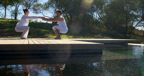 Asian adults practicing tai chi on deck by water