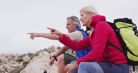 Senior couple hiking in mountainous landscape, pointing ahead