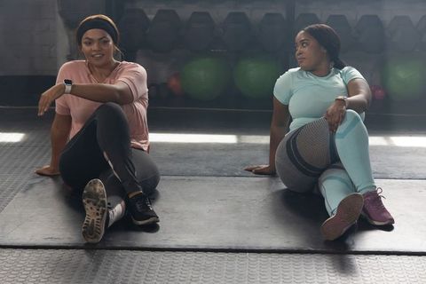 African american women stretching on gym mats for post-workout recovery and camaraderie