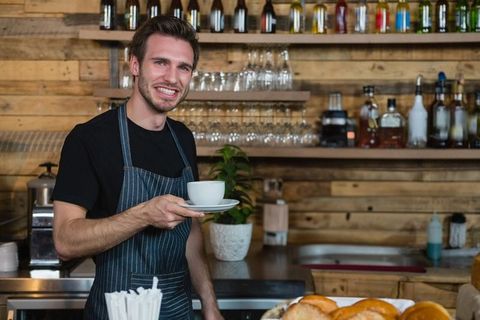 Smiling Barista Serving Coffee Among Pastries in Rustic Cafe