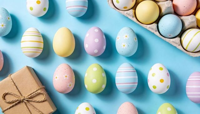 Pastel Easter Eggs Arranged in Rows on Blue Flatlay with Kraft Gift Box