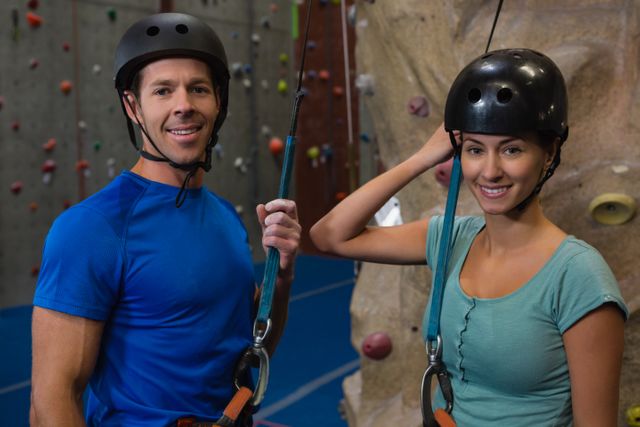 Portrait of athletes in sports helmet standing by climbing wall at fitness studio