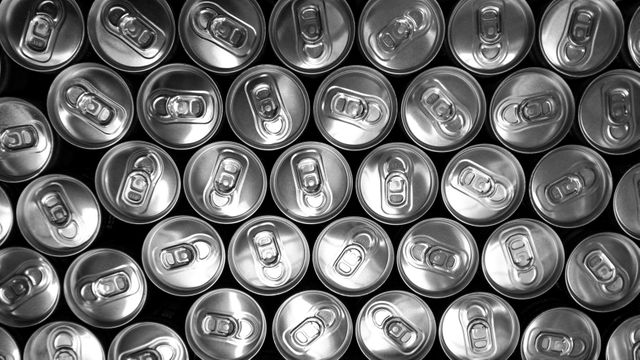 Top view of numerous soda cans forming a symmetrical pattern with their silver aluminum tops. Perfect for illustrating beverage industry topics, environmentally friendly packaging, or discussions on recycling and manufacturing materials.