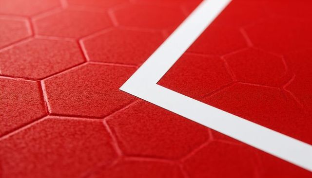 White right-angle stripe cutting across red hexagonal tiles macro close-up texture