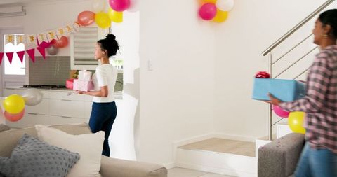 Women Decorating Living Room for Festive Celebration with Gift Boxes