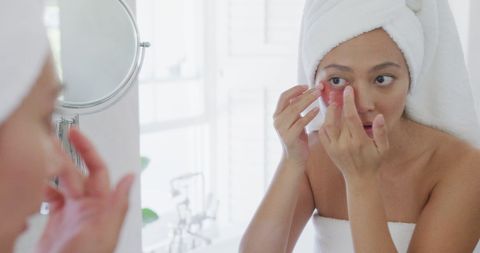 Woman applying under eye beauty mask in natural lighting