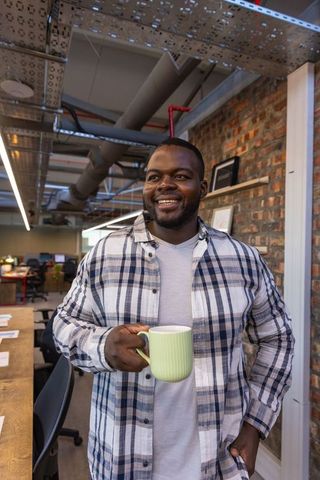 Smiling businessman with coffee mug in modern creative office