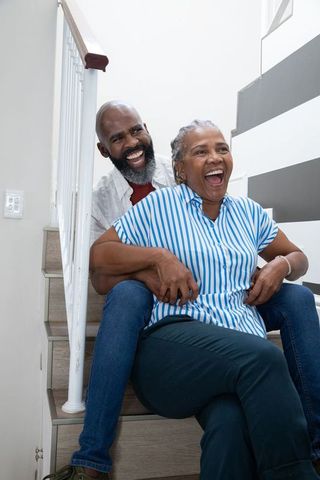 Senior African American Couple Embracing on Stairs, Genuine Joy at Home