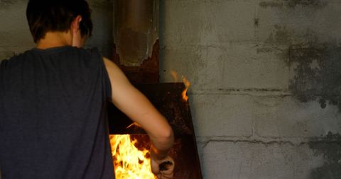 Young female metalsmith using forge to heat horseshoe