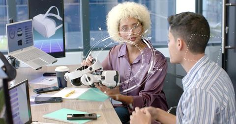 Female engineer presenting vr headset during collaborative office meeting for product demo