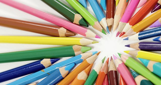 Colorful pencils are arranged in a circular pattern, converging at a central point, with copy space. The vibrant array of colors suggests creativity and the potential for artistic expression.