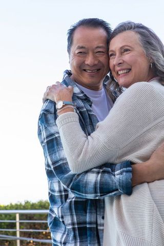 Senior Couple Sharing Loving Embrace on Sunlit Balcony