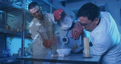 Pouring Cryogenic Liquid into Bowl while Colleague Steadying Dewar Vessel in Laboratory