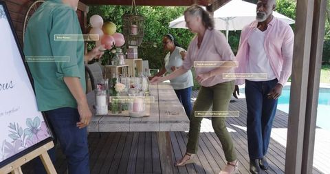 Mature Adults Arranging Outdoor Party Table by Pool with Pastel Balloons and Centerpieces