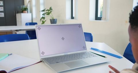 Teen studying with silver laptop on classroom desk with notebook, pencil and ruler