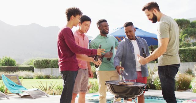 Diverse group of male friends gathering around grill, chatting and holding drinks, while cooking meat. Perfect for lifestyle blogs, social gatherings promotion, summer activity highlights, multicultural friendship representation, and casual outdoor events marketing material.