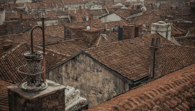 Aerial view of weathered terracotta roofs and brick chimneys in historic European town