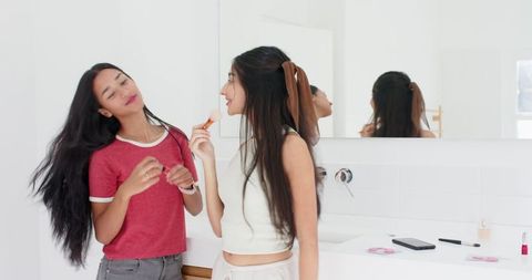 Young Women Socializing in Bathroom While Doing Makeup