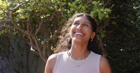 Sunlit african american woman laughing outdoors with gold necklace and hoop earrings