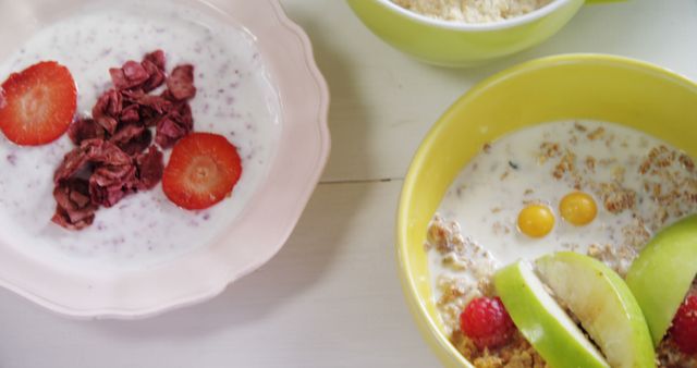 Bowls of healthy breakfast options are displayed, featuring yogurt with strawberries, cereal with milk, and fruit toppings. A balanced breakfast like this provides a nutritious start to the day with a mix of dairy, grains, and fresh fruits.