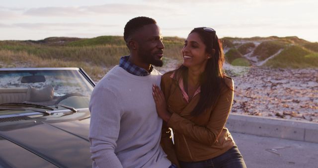 A couple sits on a car while enjoying a scenic beach sunset. This image is perfect for advertisements promoting travel, vacation packages, romantic getaways, or lifestyle blogs focusing on relationships and bonding. It can also be used in campaigns highlighting outdoor recreation and relaxation.