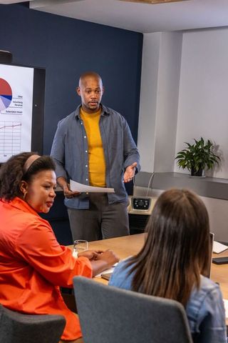 African american man presenting charts to diverse team in modern office meeting