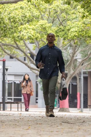 Urban professionals walking under tree canopy holding coffee cups and bags