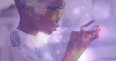 Young boy examining petri dish science experiment with digital light effects