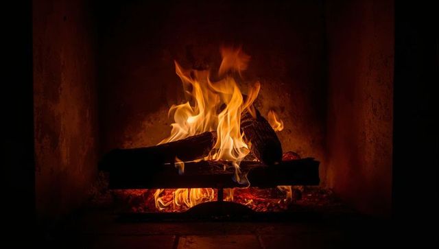 Crackling masonry fireplace with glowing embers and dancing flames on log grate