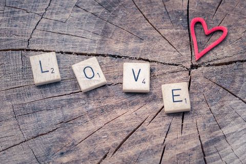 Word love spelled with scrabble tiles on rustic wooden background