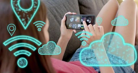 Woman tapping smartphone on couch with cloud and wi-fi overlays streaming media at home