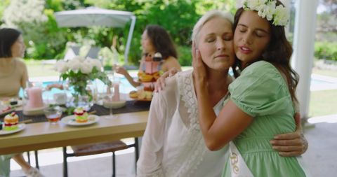 Bride Embracing Elderly Woman During Celebratory Garden Event