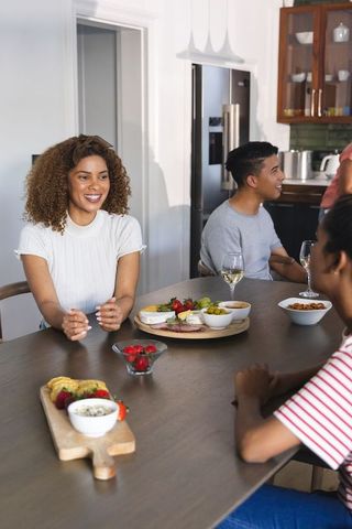 Friends laughing and sharing wine and charcuterie around modern kitchen table