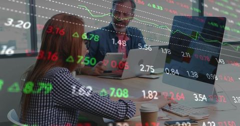 Financial team collaborating on live stock tickers across desktop and tablet in office