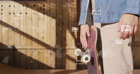 Young woman holding skateboard by wooden fence on sunlit ramp, casual denim street style