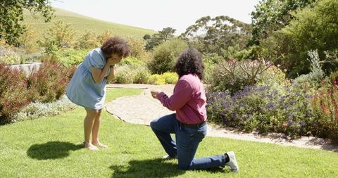 Man proposing in landscape garden setting engagement ring surprise