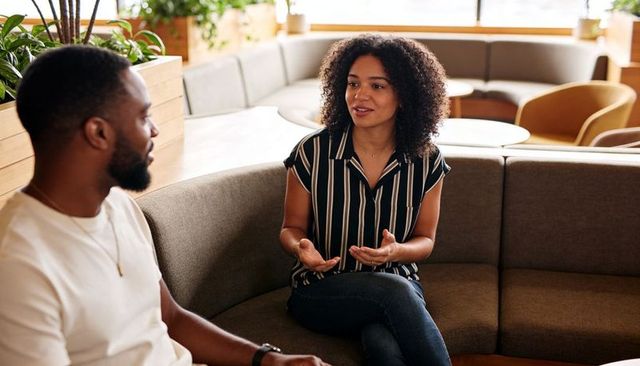 Colleagues engaging in informal conversation on modern office lounge banquette
