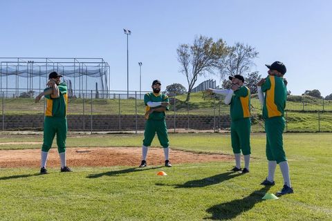 Baseball Team Warming Up Stretching on Sunny Field in Green and Yellow Uniforms