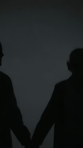 Walking couple holding hands and touching foreheads in silhouette intimate vertical video