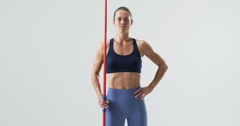 Confident female athlete holding javelin in sportswear