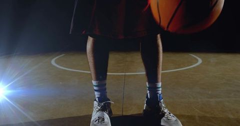 Basketball Player Holding Ball on Court with Light Flare