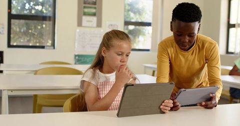 Elementary Students Collaborating on Tablets in Bright Classroom Sharing Digital Learning
