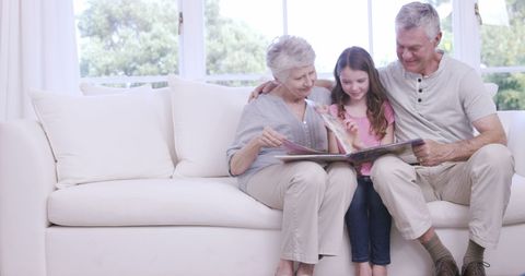 Loving Grandparents Reading Book with Granddaughter at Home