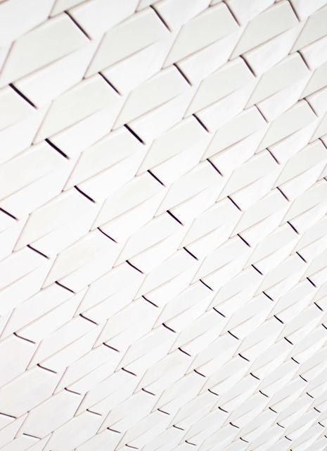 Abstract pattern of interlocking white tiles creating a seamless geometric design. Use in modern design projects, web backgrounds, or architectural presentations. Useful for adding texture and depth to various creative projects.