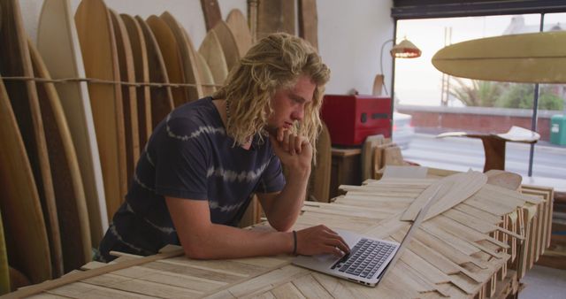 Young Man Using Laptop in Surfboard Shop - Download Free Stock Images Pikwizard.com