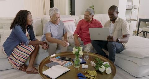 Multigenerational family choosing paint swatches and planning decor with laptop on sofa