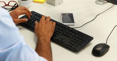 Professional working on computer in office environment with smartphone nearby